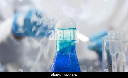 Production of detergent, blue liquid boiling and fuming in flask, chemistry Stock Photo