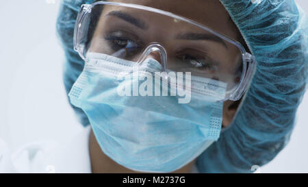 Close-up of beautiful female scientist face with security goggles, medicine Stock Photo