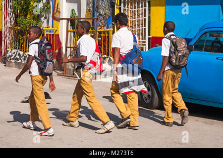 Daily life in Cuba - School boys walking past colourful Cuban artwork painted on wall at Callejon De Hamel, Havana, Cuba, West Indies Caribbean Stock Photo