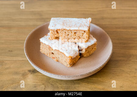 Three slices of carrot cake on a saucer and on a wooden oak table. Taken in natural light. Stock Photo