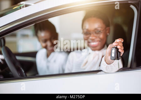 african woman with her new car showing key Stock Photo