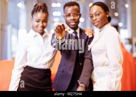 car salesman and two woman showing key of new car Stock Photo