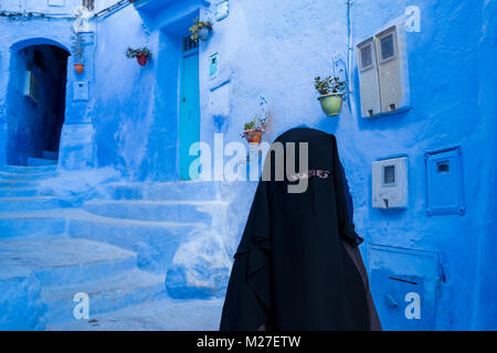 Arab woman with face covered with black niqab in Chefchaouen, the Blue city, in Morocco Stock Photo