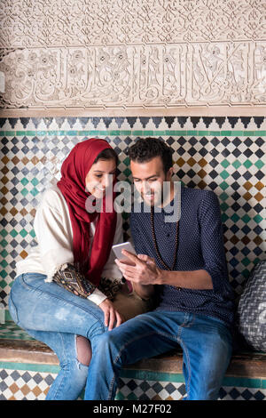 Arab couple looking at mobile phone and smiling Stock Photo