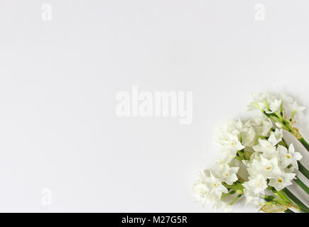 Spring styled stock photo. Easter concept. Feminine desktop scene with bouquet of narcissus, daffodil flowers on white table background. Empty space. Flat lay, top view. Stock Photo