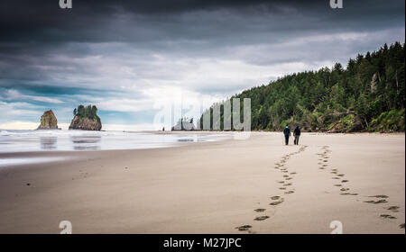 Two men walking on beach with footprints in the sand Stock Photo