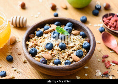 Homemade granola in wooden bowl with fresh blueberries. Healthy foods, superfood, healthy lifestyle, dieting, weight loss concept. Selective focus Stock Photo