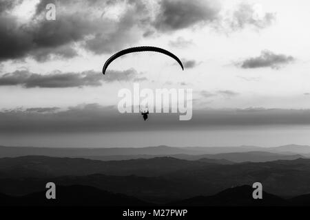 Beautiful shot of a paraglider silhouette flying over Monte Cucco (Umbria, Italy), with sunset on the background Stock Photo