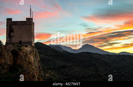 Landscape: castle of Zahara de la Sierra in the mountains. Beautiful natural views of the colorful sky during a sunset. White villages of Andalusia. Stock Photo