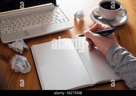 Man hand writing in planner. Coffee, laptop on background Stock Photo