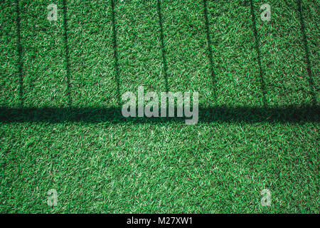 Top view close up  artificial grass or green grass texture with shadow of metal fence on grass in vintage style. Stock Photo