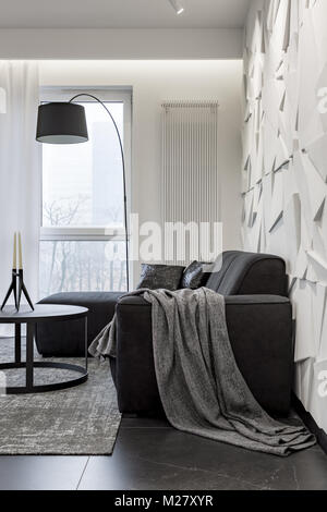 Black corner sofa and decorative white wall in modern living room Stock Photo