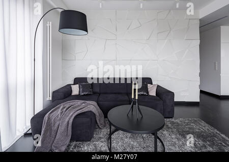 Black corner sofa, coffee table and arc floor lamp in modern apartment Stock Photo