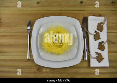 Easter time table place setting with decorations of a nest and chocolate Easter eggs Stock Photo