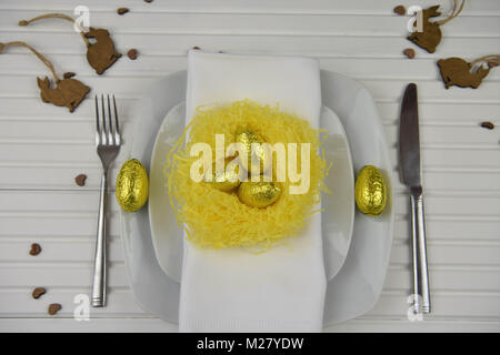 Easter time table place setting with decorations of a nest and chocolate Easter eggs Stock Photo