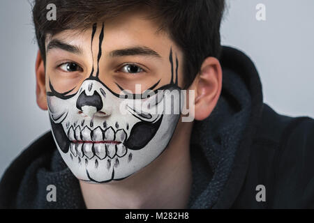 Portrait of a beautiful teenager with a makeup on his face in the style of Halloween. Close-up photo Stock Photo