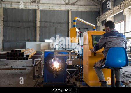 worker sits behind a remote control gas welding machine. pipe cutting system Stock Photo