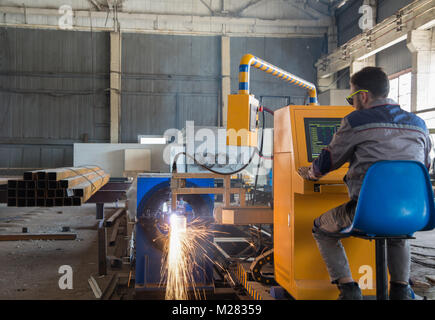 worker sits behind a remote control gas welding machine. pipe cutting system Stock Photo