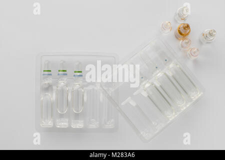 Medical vials with liquid for injection in plastic containers on a white background. The view from the top Stock Photo