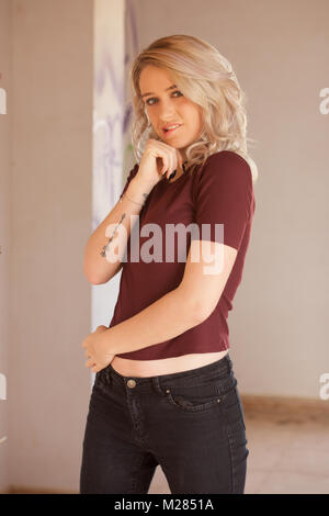 Beautiful blonde girl wearing black jeans and a top - interior location Stock Photo