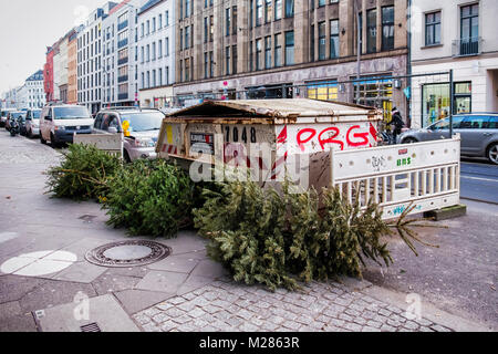 Abandoned,dumped,discarded,trashed Chritmas trees and Dumpster in a city street after Christmas. Mitte,Berlin Stock Photo