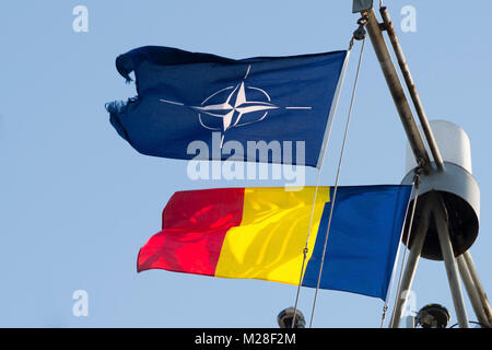 CONSTANTA, Romania, Feb 1. 2018.  Romanian and NATO flags wave in the wind as Standing NATO Mine Countermeasure Group Two makes a port visit at Constanta harbor on the Black Sea. NATO Stock Photo