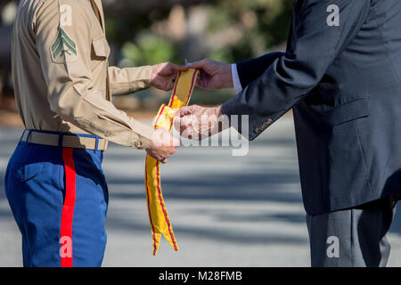 U.S. Marine Corps Cpl. Juan Garcia, left, a motor vehicle operator with Headquarters Battalion, 1st Marine Division (MARDIV), gives a China service streamer to Jean White, a 1st MARDIV veteran, during the unit's the 77th anniversary ceremony at Marine Corps Base Camp Pendleton, Calif., Feb. 2, 2018. Division veterans, active duty Marines and Sailors participated in the ceremony, celebrating the oldest, largest and most decorated division in the Marine Corps. (U.S. Marine Corps Stock Photo