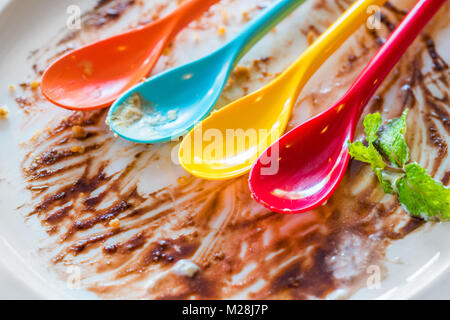 close up of eaten chocolate sauce with colorful spoon on dish Stock Photo