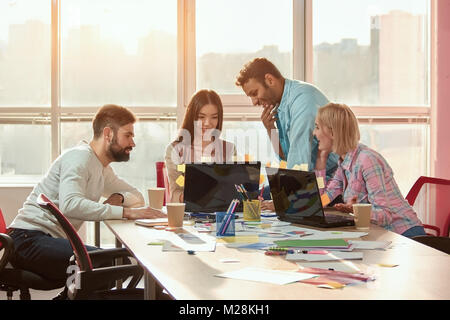 Web designers creating new concept together. Female and male colleagues communicate during work break sitting in coworking space. Stock Photo
