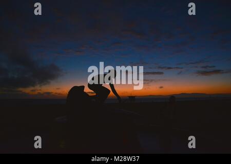 Surfing at Sunset. Young Man Riding Wave at Sunset. Outdoor Active Lifestyle. Stock Photo