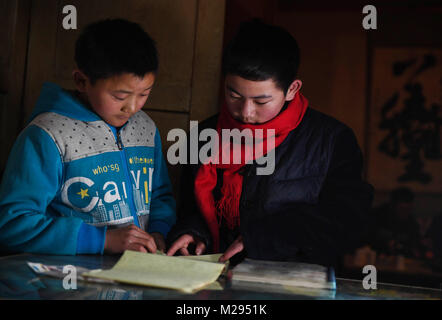 (180206) -- KANGLE, Feb. 6, 2018 (Xinhua) -- Sun Jianjun (R) and his younger brother Sun Jianqiang discuss homework at home in Xinzhuang Village, Basong Township, Kangle County of northwest China's Gansu Province, Feb. 2, 2018.   Spring Festival, or Chinese Lunar New Year, falls on Feb. 16 this year. Hundreds of millions of Chinese will return to their hometowns for family gatherings.    14-year-old Sun Jianjun and his 15 schoolmates are among these travellers eager back to home. On Feb. 1, the first day of the 2018 Spring Festival travel rush, they stepped onto a train in Nantong of east Chin Stock Photo