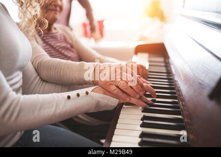 A girl with grandmother playing the piano. Stock Photo