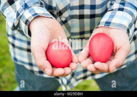 Easter hunt - two red eggs in child hands Stock Photo