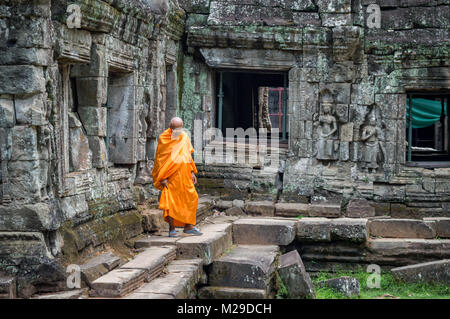 Monk in orange robe in an ancient temple in Angkor Wat, Siem Rep, Cambodia Stock Photo