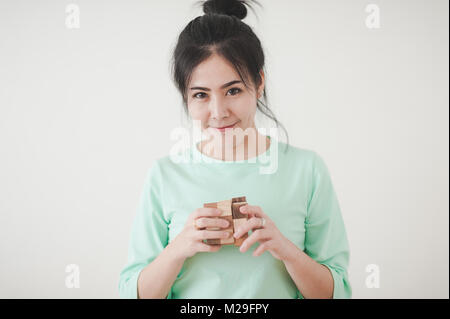 Young Attractive Asian woman wear green shirt playing wooden rubik's cube with positive emotion. Preblem solving abstract concept Stock Photo