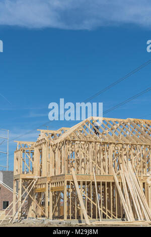 Wood frame house under construction with builder roofing. New two-story stick built next to completed homes in Irving, Texas, USA. Joist, timber frame Stock Photo