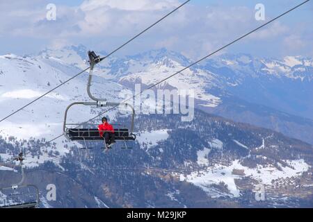 VALMEINIER, FRANCE - MARCH 24, 2015: Skier goes up the lift in Galibier-Thabor station in France. The station is located in Valmeinier and Valloire an Stock Photo