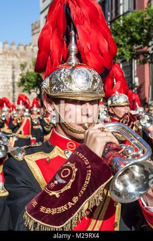 Portrait of a musician of a music band with a red feathered helmet performing a processional march during a procession of Holy Week. Stock Photo