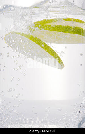 Lime slices into carbonated water with bubbles. Cold drink and refreshment close up Stock Photo