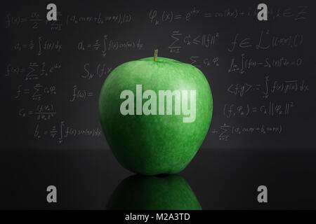Green apple on black table against blackboard full of complicated mathematical formulas. Knowledge and education theme. (Text it's some math magic abo Stock Photo