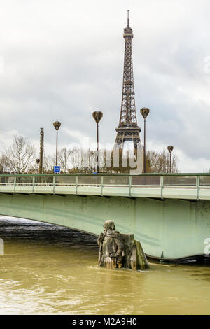 The Alma bridge and the half immersed statue 'Le Zouave' during a winter flood of the Seine with the Eiffel tower in the distance under a cloudy sky. Stock Photo