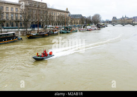 Paris, France - January 29, 2018: Divers from the Paris Fire Brigade, very busy during the flooding of the Seine, go up the river at full speed on a b Stock Photo