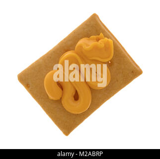 A single hard bread cracker with canned cheddar cheese squirted on top isolated on a white background. Stock Photo