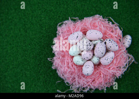 Easter time with a nest full of pink and white Easter eggs on a green grass spring time background Stock Photo