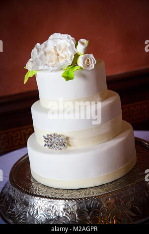 Three tiered white icing wedding cake with iced flower decoration Stock Photo