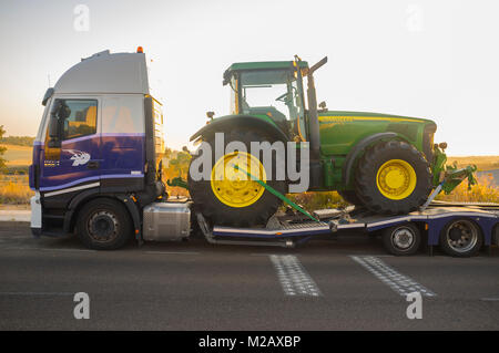 Badajoz, Spain - August 6th, 2017: Auto-transport trailer carrying the Row Crop Tractor John Deere 8320 Stock Photo