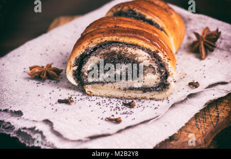 baked roll with poppy seeds on a wooden board, close up Stock Photo