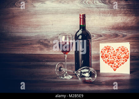Red wine bottle, two glasses of red wine with a love message on wooden table. Valentines day celebration concept. Copy space. Stock Photo