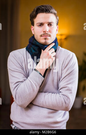 Young man with scarf, holding his neck because of throat ache Stock Photo