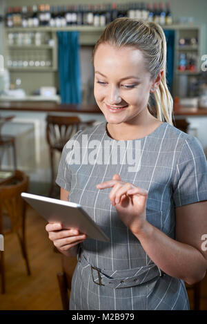 Female Manager In Restaurant Using Digital Tablet Stock Photo